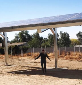 Owner of ParagonSun standing under ground mount solar panel installation